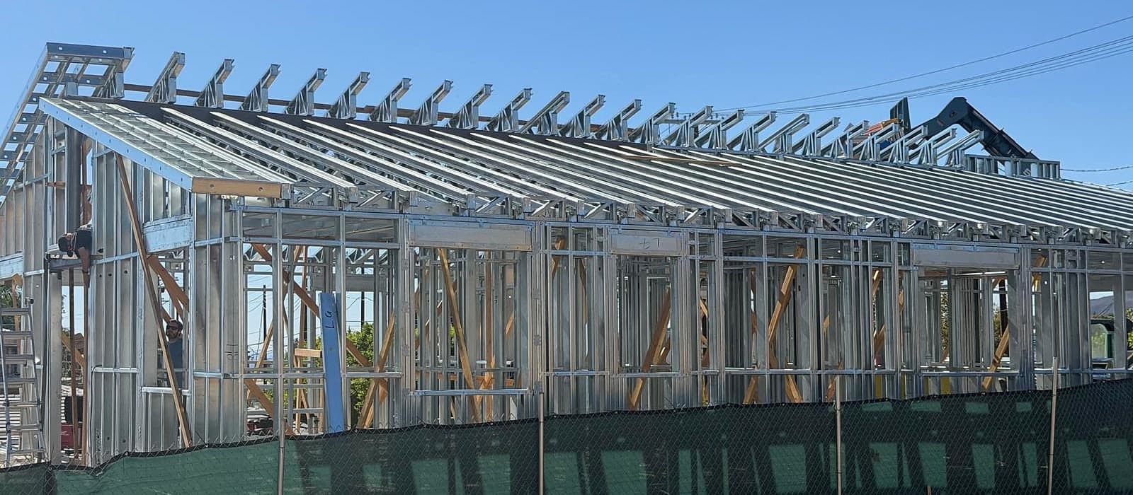 The same frame on site, in galvanized steel Job-site photo of the same house in Pacific Palisades framed in light-gauge steel, with the roof framing complete